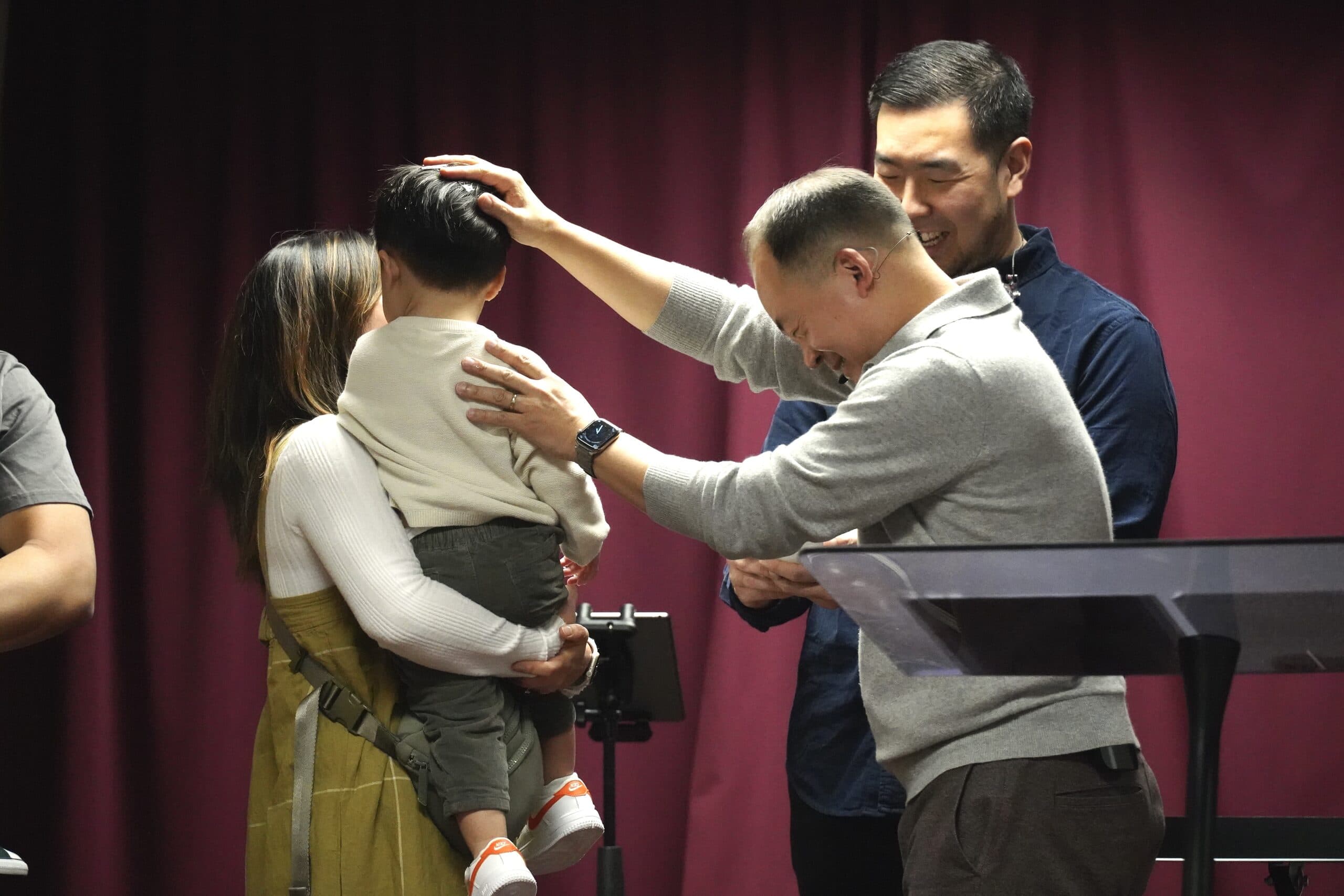 A pastor praying over a young child held by a parent during a Metro service